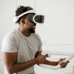 Smiling man playing with VR headset and controller, enjoying immersive experience.